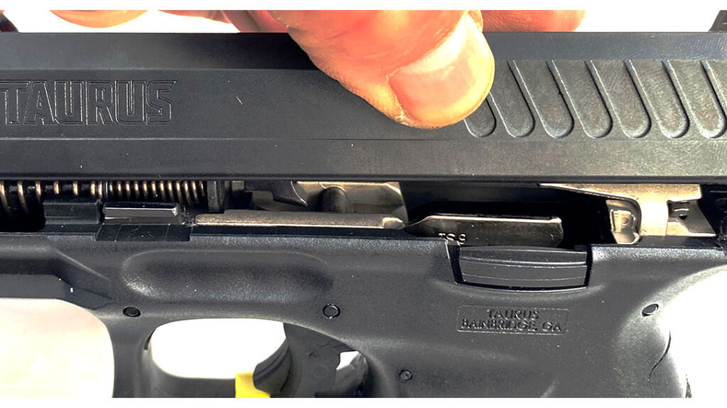 Dismounted slide tilted to show the relationship of the barrel retaining pin, barrel unlocking cam, and frame cam pin. For efficiency of manufacture, the pistol uses many MIM cast parts and sheet metal stampings.