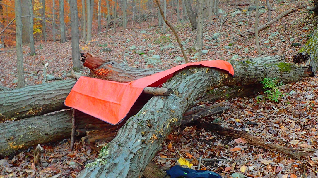 The author used a thick, All-weather blanket (tarp) as the primary covering and camouflaged it with natural materials.