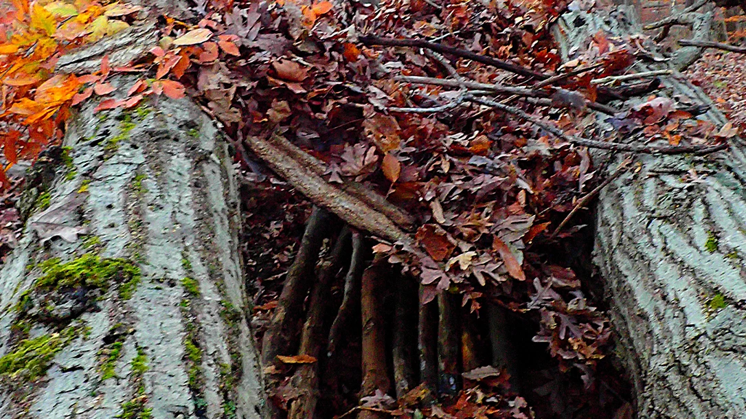 Debris was scattered on the orange tarp until it blended with the environment. The author added bark to keep leaves from blowing away.