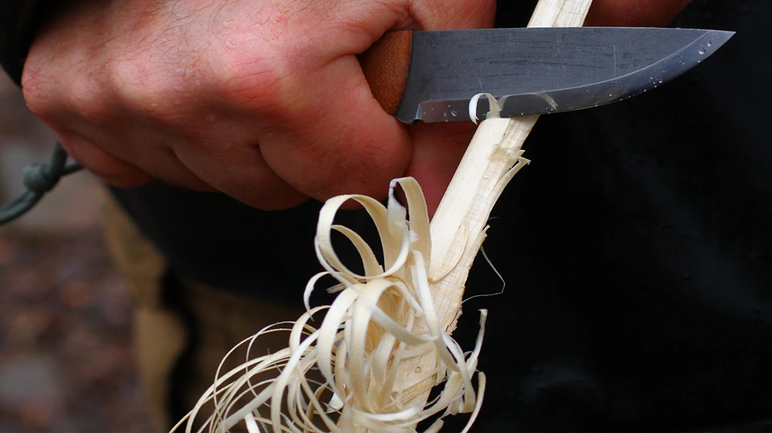 Use a full-fist grip when feathering wood, and let the blade make thin curls using the knife's curve.